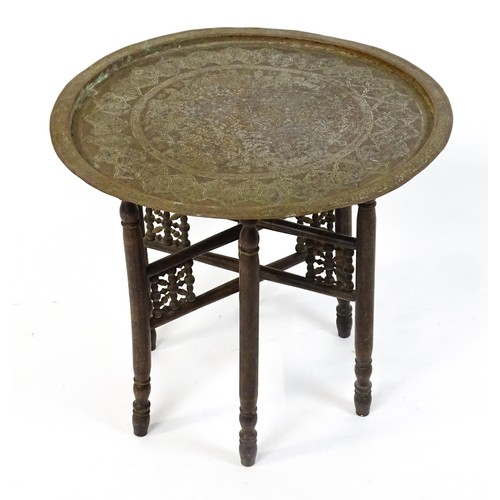 243 - An Islamic brass top table with a folding base. 25