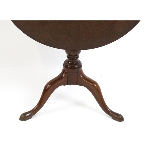 1710 - A Georgian mahogany tripod table with a one plank top above a turned pedestal base and raised on thr... 