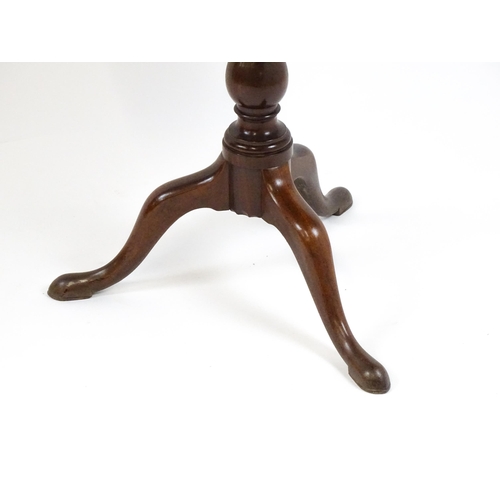 1710 - A Georgian mahogany tripod table with a one plank top above a turned pedestal base and raised on thr... 