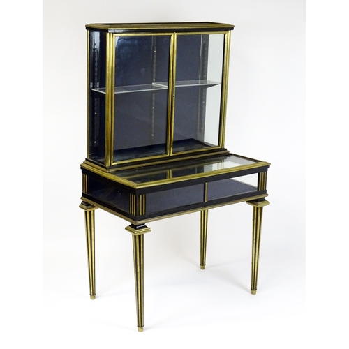 1758 - A 19hC vitrine with two glass doors lined with brass mouldings above a base with a hinged lid and ra... 