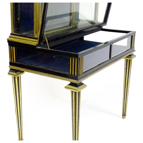 1758 - A 19hC vitrine with two glass doors lined with brass mouldings above a base with a hinged lid and ra... 