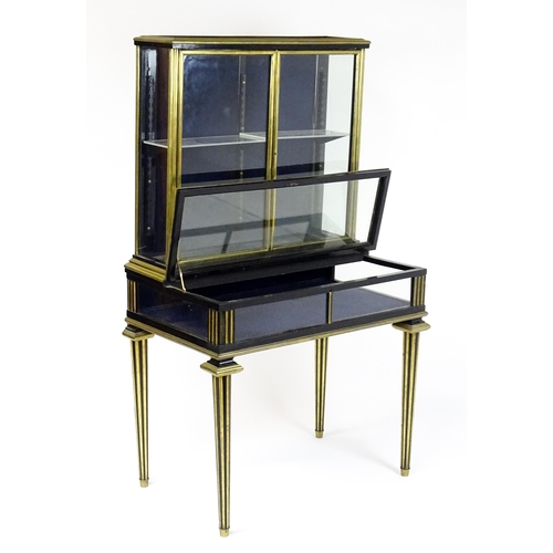 1758 - A 19hC vitrine with two glass doors lined with brass mouldings above a base with a hinged lid and ra... 