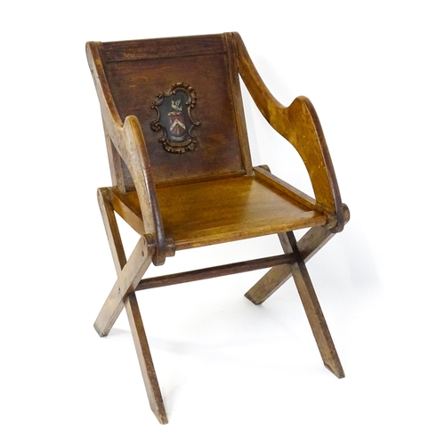 1760 - A late 19thC / early 20thC oak Glastonbury chair with a painted armorial to the centre of the backre... 