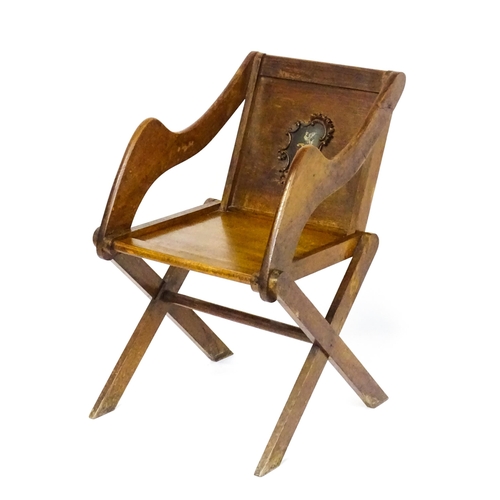 1760 - A late 19thC / early 20thC oak Glastonbury chair with a painted armorial to the centre of the backre... 