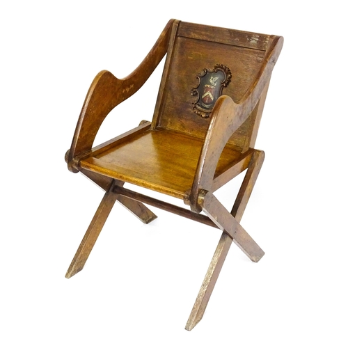 1760 - A late 19thC / early 20thC oak Glastonbury chair with a painted armorial to the centre of the backre... 