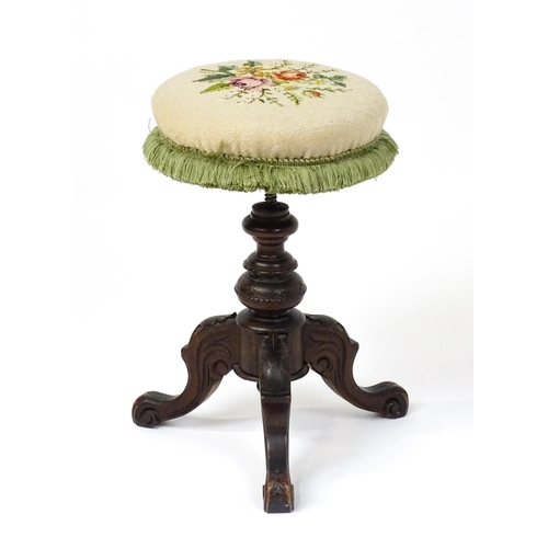 1764 - A late 19thC walnut piano stool with an adjustable needlework top raised on three carved cabriole le... 