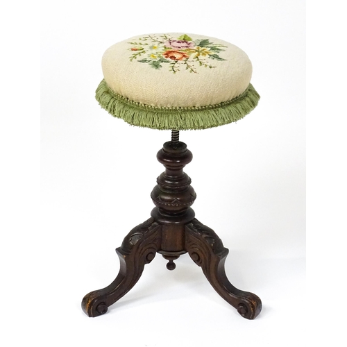 1764 - A late 19thC walnut piano stool with an adjustable needlework top raised on three carved cabriole le... 