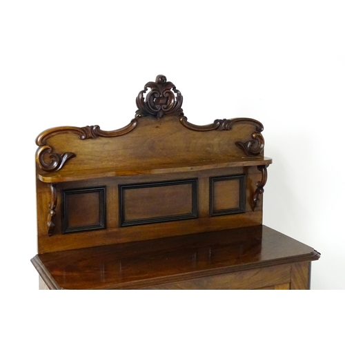 1796 - A small Victorian mahogany chiffonier with a carved upstand having a small shelf and two panelled cu... 