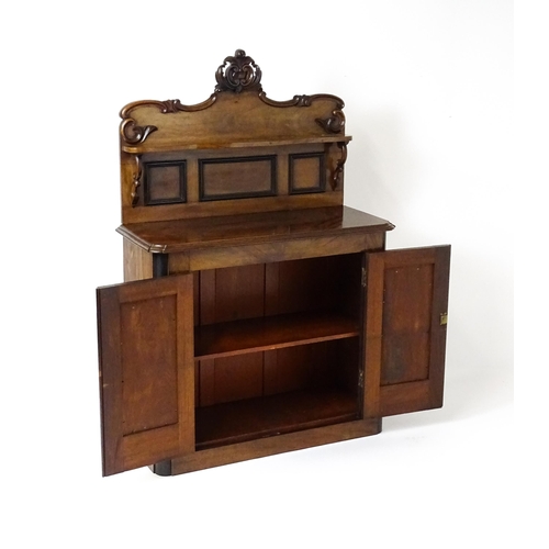 1796 - A small Victorian mahogany chiffonier with a carved upstand having a small shelf and two panelled cu... 