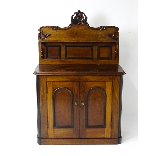 1796 - A small Victorian mahogany chiffonier with a carved upstand having a small shelf and two panelled cu... 