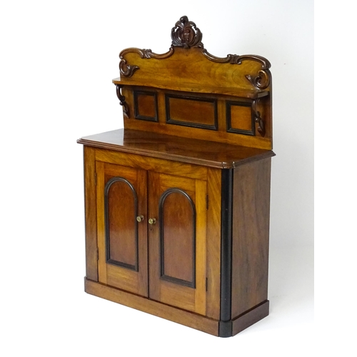 1796 - A small Victorian mahogany chiffonier with a carved upstand having a small shelf and two panelled cu... 