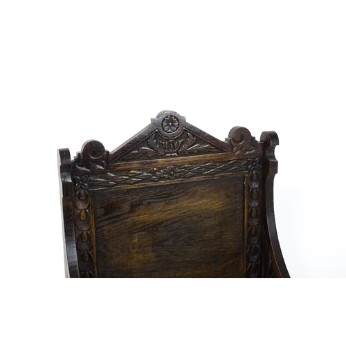 1797 - A Victorian carved oak chair with a pointed pediment above a panelled backrest and floral carved sea... 