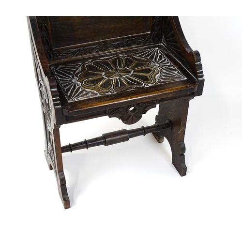 1797 - A Victorian carved oak chair with a pointed pediment above a panelled backrest and floral carved sea... 