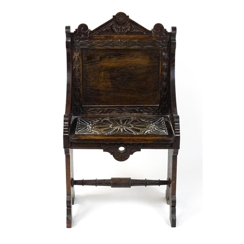 1797 - A Victorian carved oak chair with a pointed pediment above a panelled backrest and floral carved sea... 