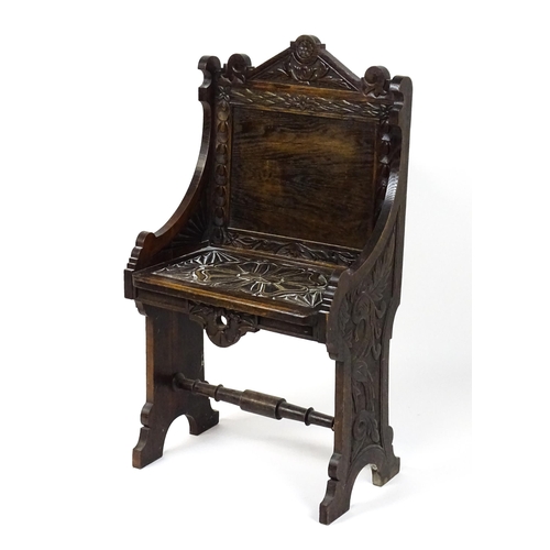 1797 - A Victorian carved oak chair with a pointed pediment above a panelled backrest and floral carved sea... 