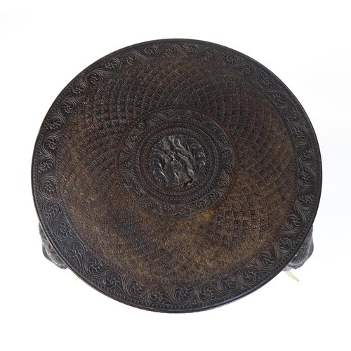 1804 - An early 20thC Anglo Indian occasional table with a carved, scrolled top above four elephant formed ... 