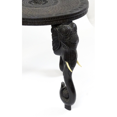 1804 - An early 20thC Anglo Indian occasional table with a carved, scrolled top above four elephant formed ... 