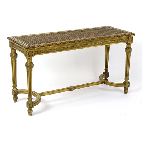 1808 - A 19thC gilt stool with a caned seat raised on four turned tapering legs with fluted decoration and ... 