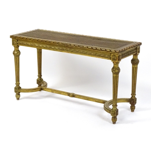 1808 - A 19thC gilt stool with a caned seat raised on four turned tapering legs with fluted decoration and ... 