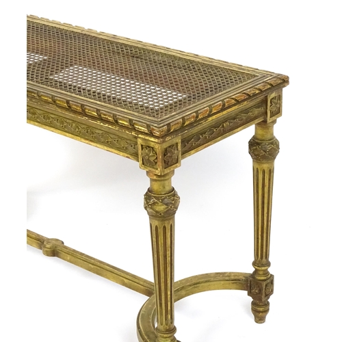 1808 - A 19thC gilt stool with a caned seat raised on four turned tapering legs with fluted decoration and ... 