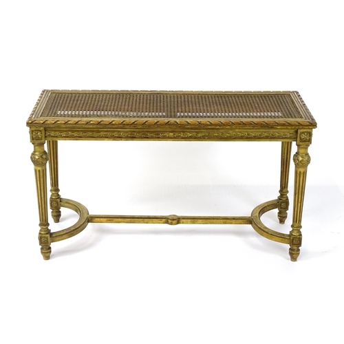 1808 - A 19thC gilt stool with a caned seat raised on four turned tapering legs with fluted decoration and ... 