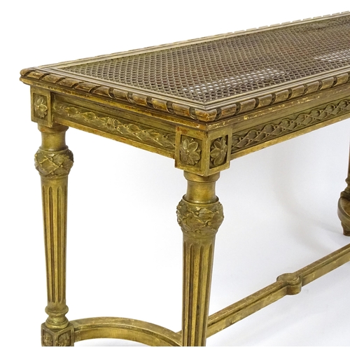 1808 - A 19thC gilt stool with a caned seat raised on four turned tapering legs with fluted decoration and ... 