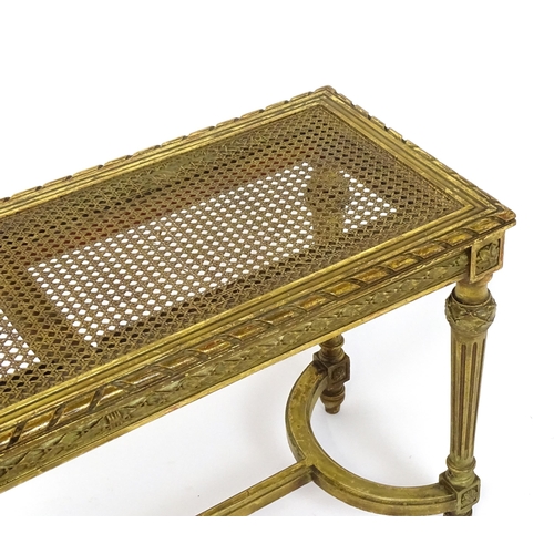 1808 - A 19thC gilt stool with a caned seat raised on four turned tapering legs with fluted decoration and ... 