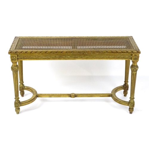 1808 - A 19thC gilt stool with a caned seat raised on four turned tapering legs with fluted decoration and ... 