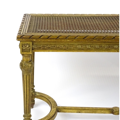 1808 - A 19thC gilt stool with a caned seat raised on four turned tapering legs with fluted decoration and ... 