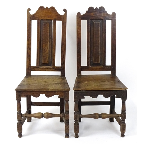 1817 - A pair of 18thC oak side chairs with scrolled cresting rails, panelled backrests and seats raised on... 