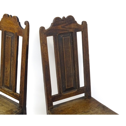 1817 - A pair of 18thC oak side chairs with scrolled cresting rails, panelled backrests and seats raised on... 