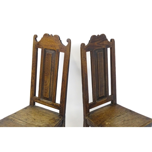 1817 - A pair of 18thC oak side chairs with scrolled cresting rails, panelled backrests and seats raised on... 