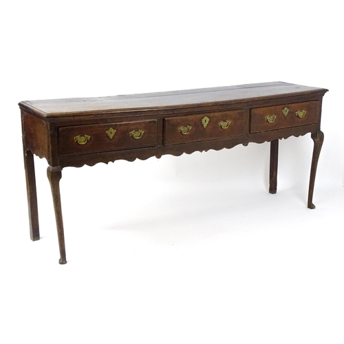 1818 - An 18thC oak dresser base with brass swan neck handles and back plates, the dresser raised on cabrio... 