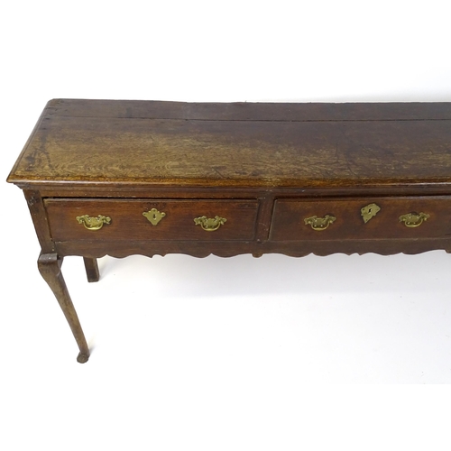 1818 - An 18thC oak dresser base with brass swan neck handles and back plates, the dresser raised on cabrio... 