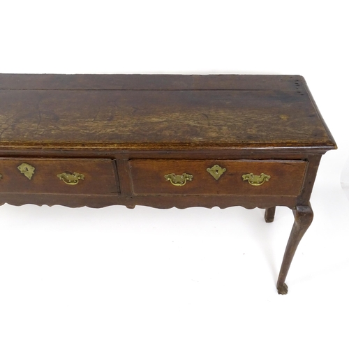 1818 - An 18thC oak dresser base with brass swan neck handles and back plates, the dresser raised on cabrio... 