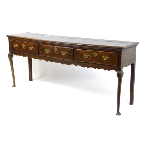 1818 - An 18thC oak dresser base with brass swan neck handles and back plates, the dresser raised on cabrio... 