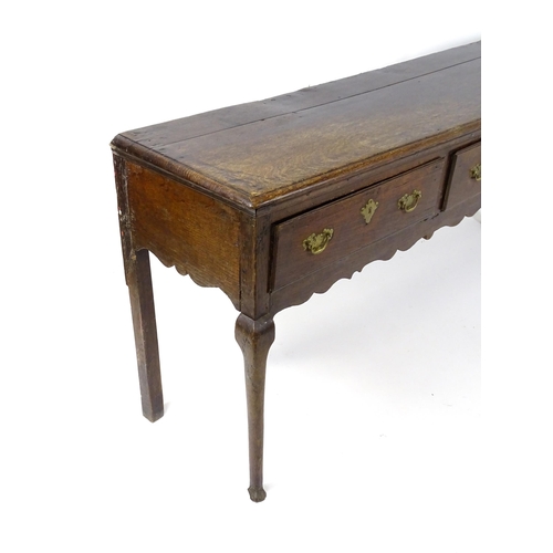 1818 - An 18thC oak dresser base with brass swan neck handles and back plates, the dresser raised on cabrio... 