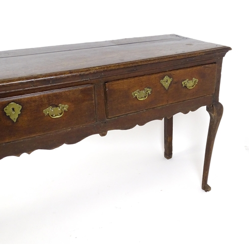 1818 - An 18thC oak dresser base with brass swan neck handles and back plates, the dresser raised on cabrio... 