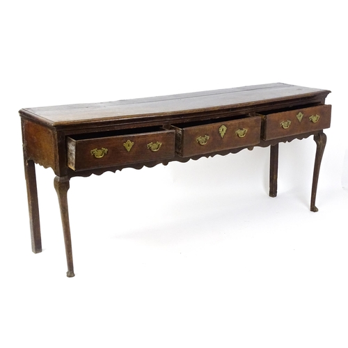 1818 - An 18thC oak dresser base with brass swan neck handles and back plates, the dresser raised on cabrio... 