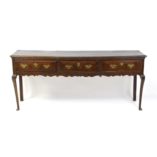 1818 - An 18thC oak dresser base with brass swan neck handles and back plates, the dresser raised on cabrio... 