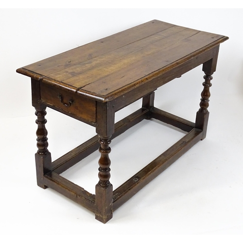 1822 - An 18thC oak side table with a planked top above a single frieze drawer raised on four block and tur... 