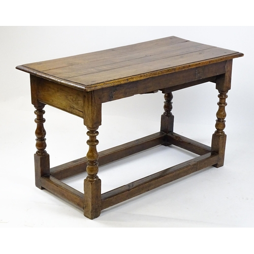 1822 - An 18thC oak side table with a planked top above a single frieze drawer raised on four block and tur... 