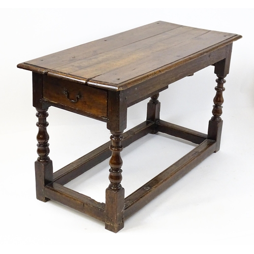 1822 - An 18thC oak side table with a planked top above a single frieze drawer raised on four block and tur... 