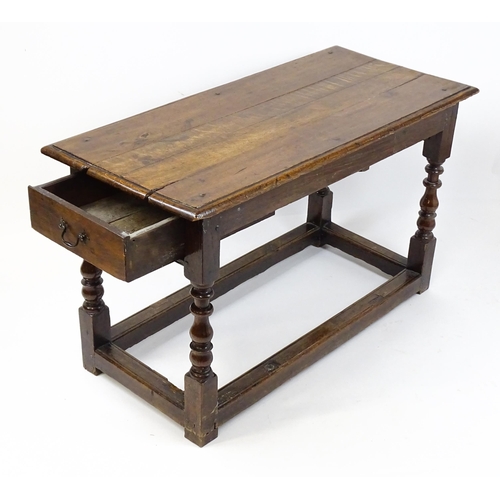 1822 - An 18thC oak side table with a planked top above a single frieze drawer raised on four block and tur... 