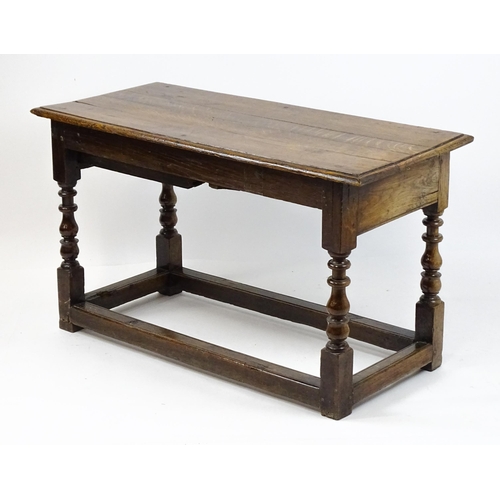 1822 - An 18thC oak side table with a planked top above a single frieze drawer raised on four block and tur... 