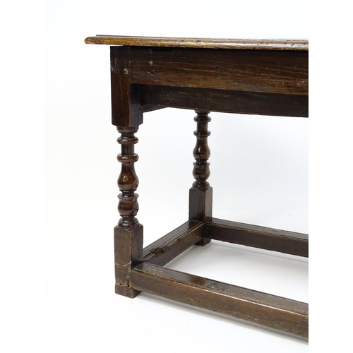 1822 - An 18thC oak side table with a planked top above a single frieze drawer raised on four block and tur... 