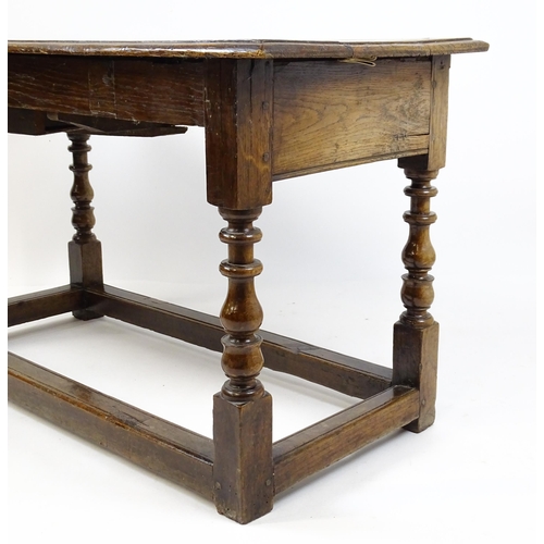 1822 - An 18thC oak side table with a planked top above a single frieze drawer raised on four block and tur... 