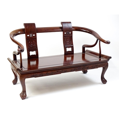 1842 - An early 20thC Chinese elm bench with scrolled arms,, carved pierced back rests  and raised on four ... 