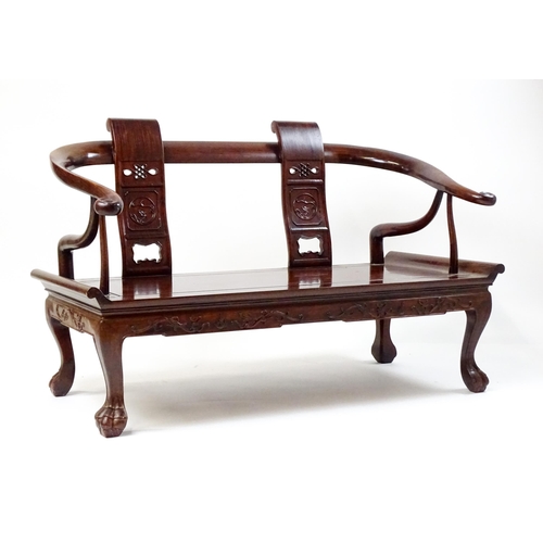 1842 - An early 20thC Chinese elm bench with scrolled arms,, carved pierced back rests  and raised on four ... 