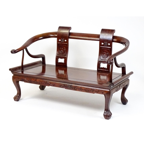 1842 - An early 20thC Chinese elm bench with scrolled arms,, carved pierced back rests  and raised on four ... 